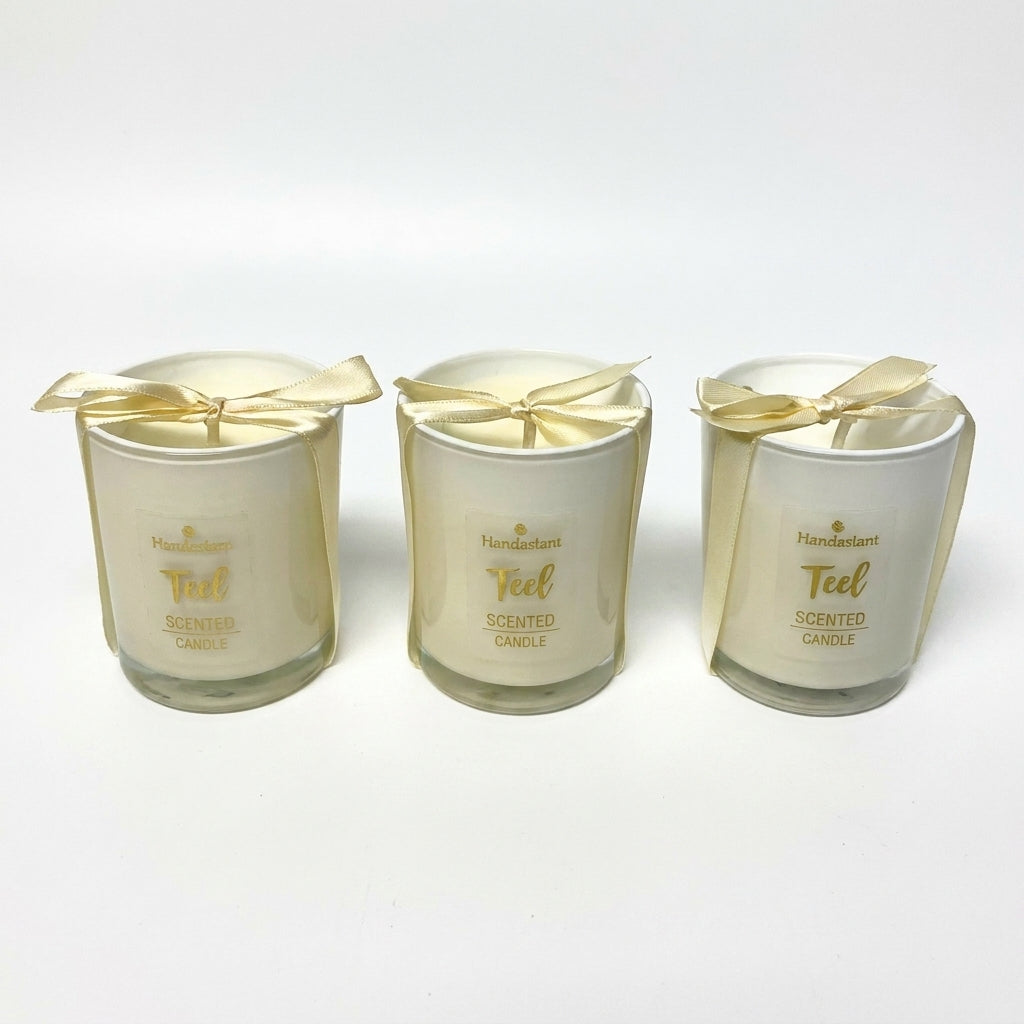 Set of 3 Handastant Teel scented candles in cream glass jars with golden ribbon bows