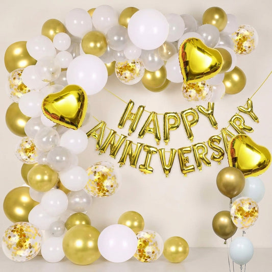 Gold and white Happy Anniversary foil balloon decoration set with heart balloons and confetti balloons arranged on white wall