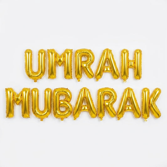 Gold foil letter balloons spelling "UMRAH MUBARAK" on white background