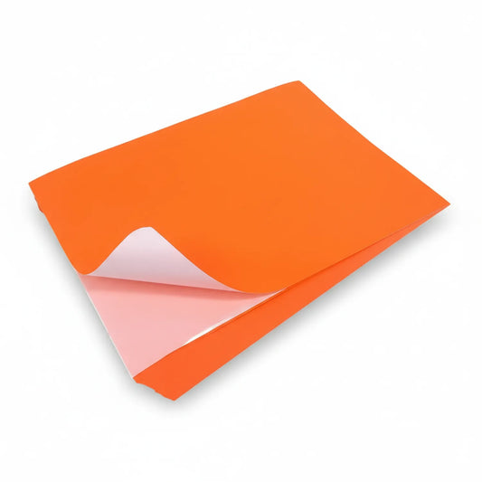 Orange fluorescent paper sheet with pink adhesive backing peeling corner, self-adhesive craft paper for art and stationery projects