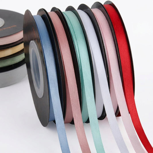 Eight spools of colorful decorative ribbons in blue, rose, pink, mint, white, lavender, and red arranged in a fan display