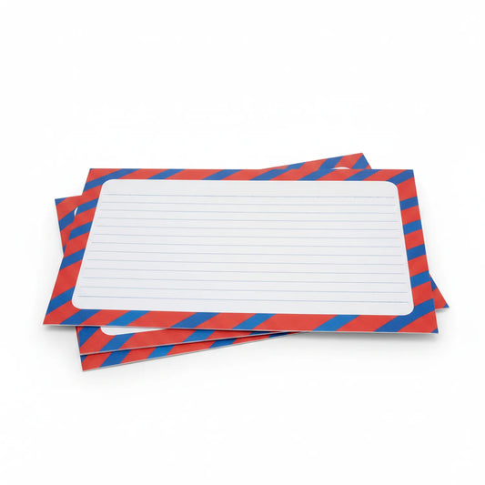 Stack of Sheet Assignment Colored Notepads with red and blue diagonal stripe pattern and white lined pages visible on top sheet